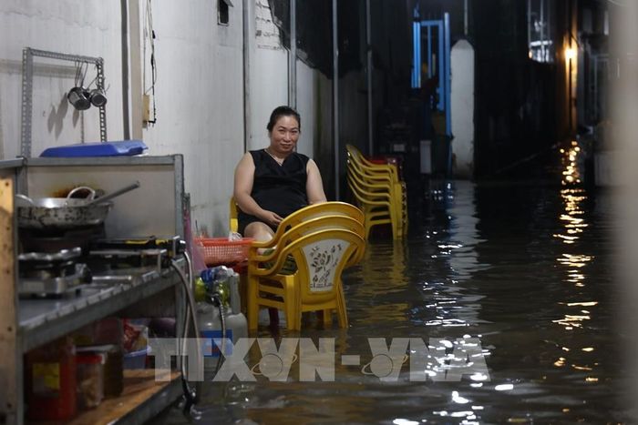 Chị Nguyễn Thị Cẩm Ly chờ khách trong cảnh ngập nước. Ảnh: Hồng Đạt - TTXVN 