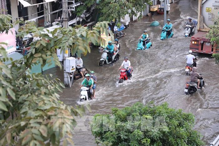 Các phương tiện lưu thông trên đường Trần Xuân Soạn, phường Tân Thuận, bị ngập do triều cường chiều 11/10. Ảnh: Hồng Đạt - TTXVN 