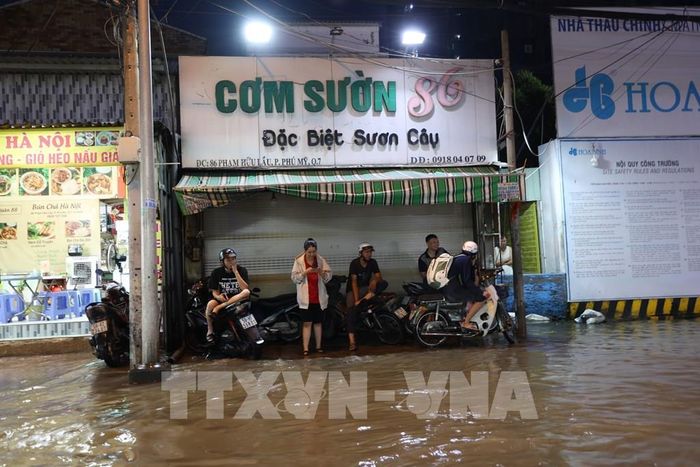Nhiều người dân phải ngừng di chuyển, chờ đợi nước rút dần trên đường Phạm Hữu Lầu, phường Tân Mỹ, ngập sâu do triều cường tối 11/10. Ảnh: Hồng Đạt - TTXVN 