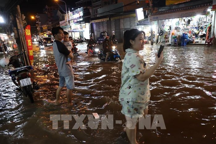 Người dân sống ở khu vực đường Phạm Hữu Lầu, phường Tân Mỹ, đã quen với tình trạng ngập nước do triều cường. Ảnh: Hồng Đạt - TTXVN 