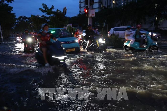 Các phương tiện di chuyển qua khu vực ngã tư Nguyễn Lương Bằng - Hoàng Quốc Việt, bị ảnh hưởng nặng do triều cường tối 11/10. Ảnh: Hồng Đạt - TTXVN 