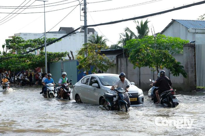 Người dân chật vật dắt bộ xe giữa ngày triều cường lên cao trên đường Lê Văn Lương.