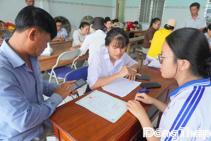  Lực lượng học sinh khối 12 hỗ trợ cài đặt tích hợp các loại giấy tờ trên ứng dụng VNeID cho người dân xã Long Bình.