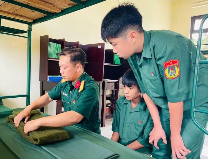 Đại úy Nguyễn Hoàng Hiệp hướng dẫn các em gấp chăn màn. Ảnh: P.D
