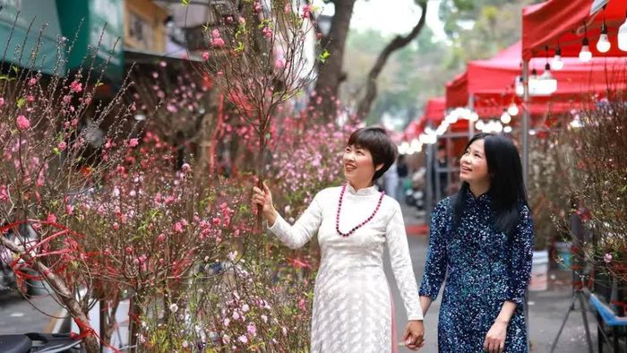 Người dân diện áo dài dạo chợ hoa đào vào dịp giáp Tết. Ảnh Hữu Nghị