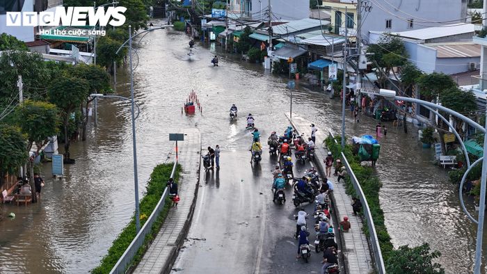 Tại nhiều đoạn đường ngập sâu, người dân phải đứng chờ nước rút mới tiếp tục di chuyển. Một số phương tiện tìm cách đi chậm qua vùng nước ngập, trong khi nhiều người lựa chọn dừng lại để tránh xe chết máy.