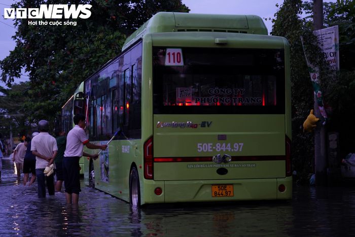 Tại khu vực ngập, một nhân viên xe buýt tranh thủ rửa xe, chờ nước rút để tiếp tục hành trình đón khách.