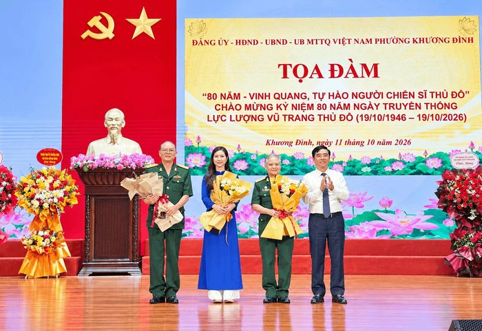 Bí thư Đảng ủy, Chủ tịch HĐND phường Khương Đình Võ Đăng Dũng tặng hoa cho nhân chứng lịch sử và đại biểu tham gia tọa đàm. Ảnh: Hồng Thái