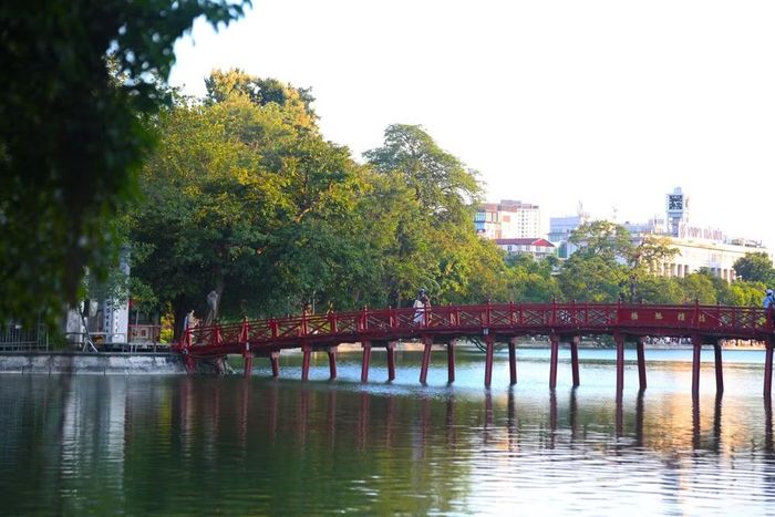 Cầu Thê Húc cong cong như dải lụa đỏ vắt ngang nền nước xanh lục của hồ Gươm, tạo nên bức tranh quang cảnh nên thơ, sống động