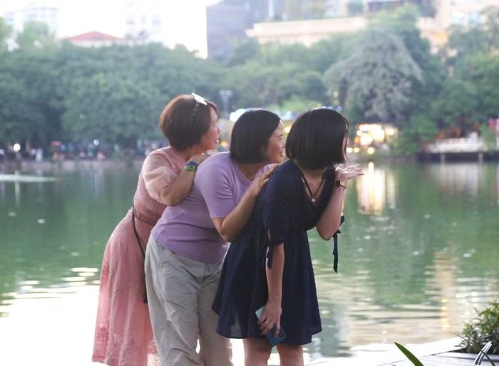 Nhóm du khách thích thú cúi người, tạo dáng vui nhộn, lưu giữ nét tươi trẻ trong chuyến dạo chơi bờ hồ