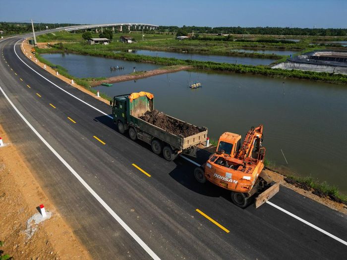 Tại khu vực tiếp giáp tỉnh Ninh Bình, các hạng mục như đắp lề đường, dựng cọc tiêu, sơn phản quang, vạch kẻ đường đang được hoàn thiện. Cùng với đó, hệ thống điện chiếu sáng và đèn tín hiệu giao thông cũng đang được triển khai. Ảnh: Đình Minh