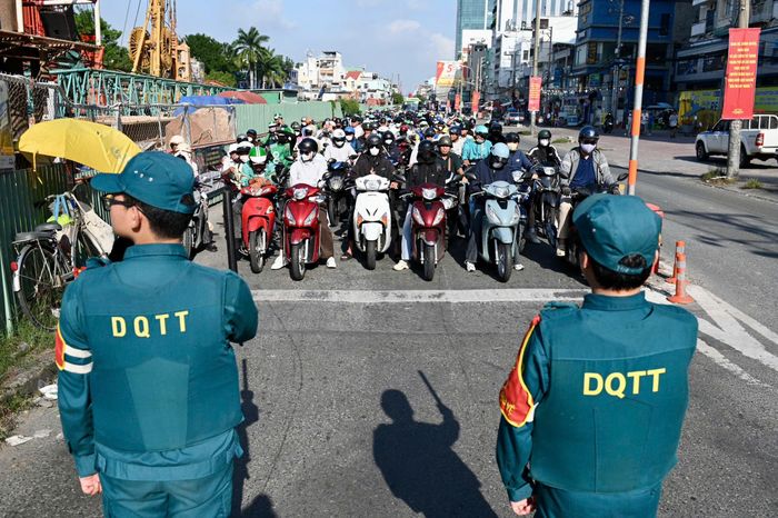  Lực lượng dân quân tự vệ phối hợp điều tiết, chỉ huy giao thông, kiểm soát đội hình và bảo đảm an ninh, trật tự trong quá trình đoàn xe di chuyển đến Nghĩa trang Liệt sĩ TP.HCM. Ảnh: Hoài Bảo.