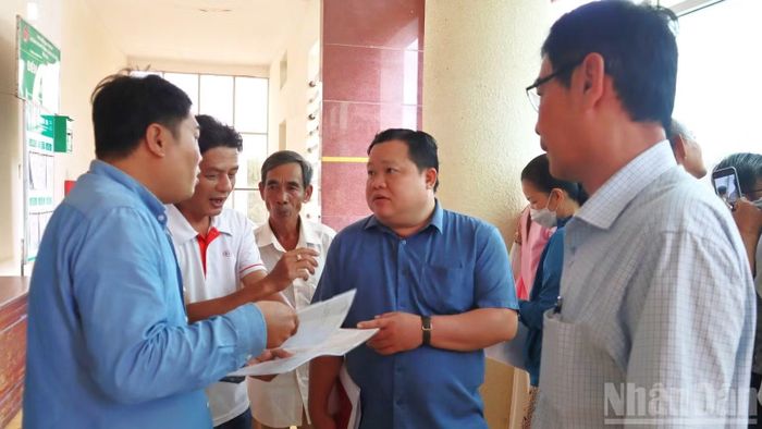 Người dân xã Bến Lức được cán bộ xã hướng dẫn, giải đáp thắc mắc trong việc làm thủ tục hành chính trong việc nhận tiền giải phóng mặt bằng. (Ảnh: THANH PHONG)