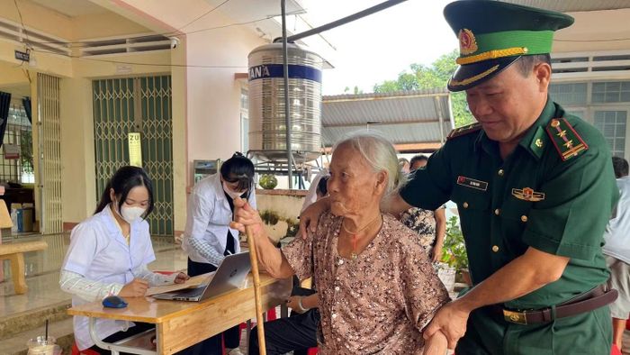 Cán bộ, chiến sĩ Đồn Biên phòng Cửa khẩu Đắk Ruê cùng với địa phương hỗ trợ đưa, đón người cao tuổi, người khuyết tật đến điểm khám. (Ảnh: NGỌC LÂN)