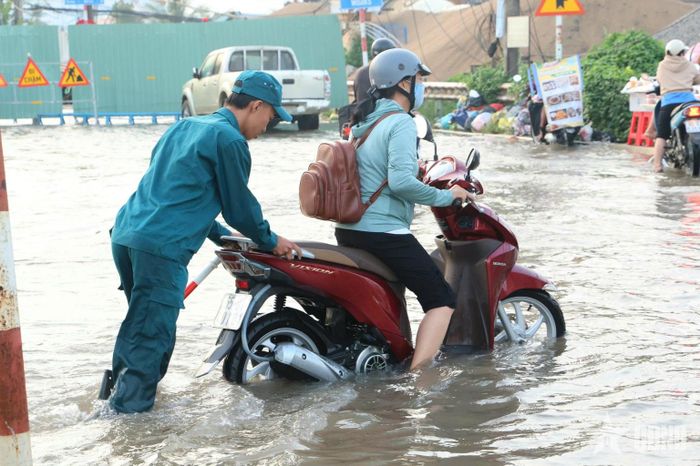 Lực lượng dân quân hỗ trợ người dân dắt xe qua điểm ngập sâu, hạn chế khó khăn khi lưu thông.