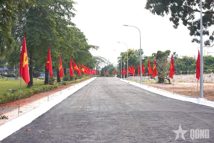 Tuyến đường nội bộ của nghĩa trang được tu bổ; bố trí cờ Đảng, cờ Tổ quốc dọc hai bên, chuẩn bị phục vụ lễ an táng hài cốt liệt sĩ. 