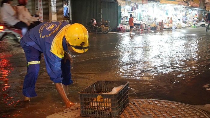  Nhân viên Công ty TNHH MTV thoát nước đô thị TPHCM khơi thông các miệng thoát nước trên đường Đoàn Trần Nghiệp (phường Thủ Dầu Một). Ảnh: DUY TRẦN 