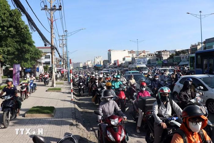 Nhiều người đi xe máy chạy lên vỉa hè để di chuyển khi đường ùn ứ. (Ảnh: Tiến Lực/TTXVN)