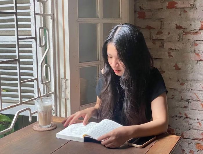Hoàng Hà chọn một góc quán quen yên tĩnh để đọc sách và thư giãn ngày cuối tuần. (Ảnh: Thanh Nga/Vietnam+)
