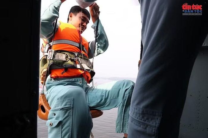 Nhân viên cứu hộ đeo dây bảo hiểm, chuẩn bị thực hiện nhiệm vụ từ cửa trực thăng.
