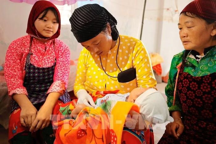 Cô đỡ Mỷ chăm sóc trẻ sơ sinh tại nhà ở thôn Cẳng Tằng, xã Lũng Cú, huyện Đồng Văn. Ảnh tư liệu: Minh Quyết/TTXVN