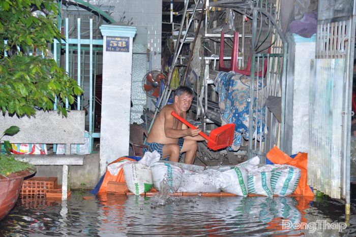 Người dân xã An Hữu dùng các vật dụng để ngăn nước tràn vào nhà.