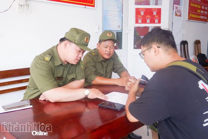Anh Đỗ Văn Thành Tài (bìa trái) hỗ trợ người dân thực hiện dịch vụ hành chính công trực tuyến tại trụ sở Công an phường Nha Trang.