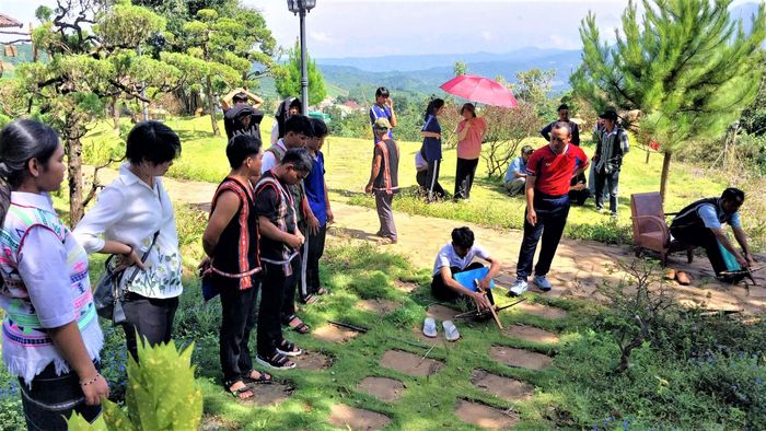 Ông Lầu Bá Tu (áo đỏ) hướng dẫn một thành viên của đội tuyển bắn ná Đinh Trang Thượng trong một buổi tập