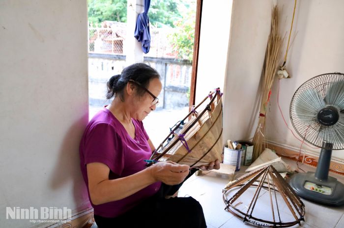 Bà Đào Thị Nên tỉ mỉ hoàn thiện lớp mo nang, công đoạn góp phần tạo độ chắc và bền tạo nên thương hiệu cho chiếc nón lá An Khoái - Văn Quán.