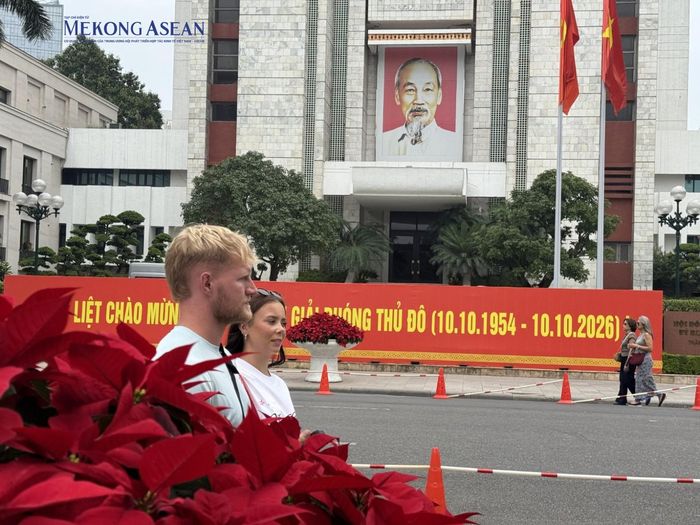  Trước trụ sở UBND thành phố Hà Nội, biểu ngữ kỷ niệm cùng hình ảnh Chủ tịch Hồ Chí Minh nổi bật giữa sắc đỏ của hoa và cờ. Người dân, du khách đi ngang qua, hòa vào nhịp sống thường ngày của Thủ đô trong những ngày thành phố đón dịp lễ lớn. 
