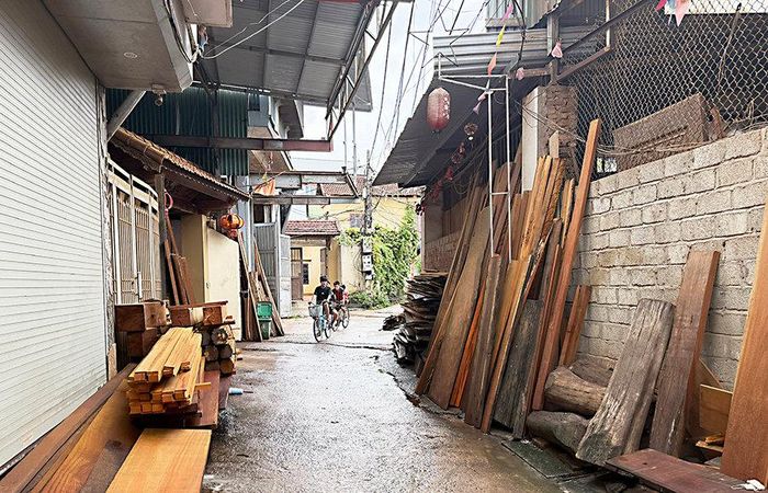 Sản xuất quy mô lớn nhưng thiếu mặt bằng tập trung khiến đường đi trong làng nghề mộc Phù Yên (xã Phú Nghĩa) được tận dụng làm nơi tập kết nguyên vật liệu gỗ. Ảnh: Thiện Mỹ