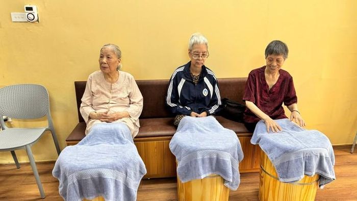 Cụ Nguyễn Thị Tần (bên trái) đang cùng các cụ khác ngâm chân tại cơ sở chăm sóc người cao tuổi ban ngày ở phường Đống Đa.