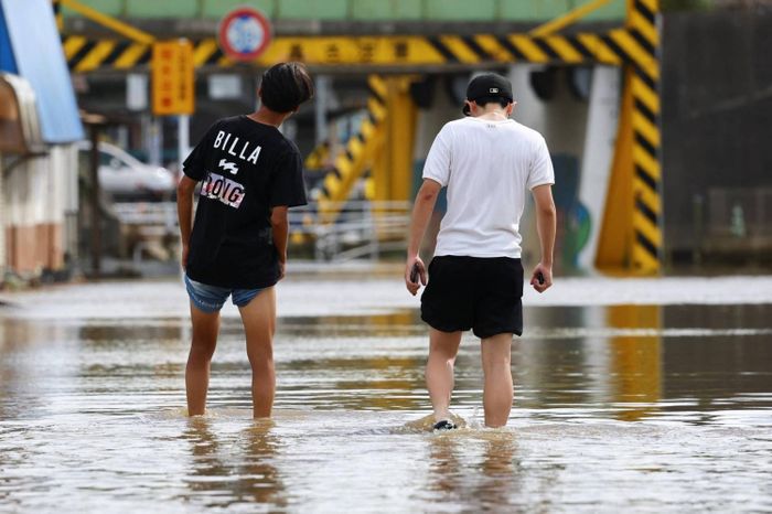 Người dân đi bộ qua khu vực bị ngập lụt ở Oami-Shirasato, tỉnh Chiba (Nhật Bản). Ảnh: Reuters.
