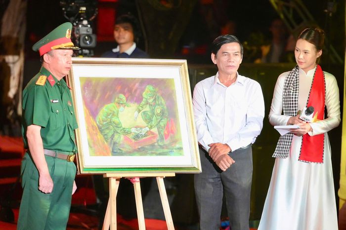  Tại đêm tri ân, họa sĩ Lê Sa Long được mời chia sẻ về quá trình khắc họa hoạt động tìm kiếm, quy tập hài cốt liệt sĩ tại Công viên Lê Thị Riêng. Họa sĩ cho biết hơn 20 bức tranh là sự kết tinh của lòng yêu nước và tình đồng đội. Toàn bộ tác phẩm được ông gửi tặng Bộ Tư lệnh TP.HCM. Trong ảnh, Đại tá Nguyễn Đình Chuẩn, Phó Chính ủy Bộ Tư lệnh TP.HCM, đại diện nhận tác phẩm. 