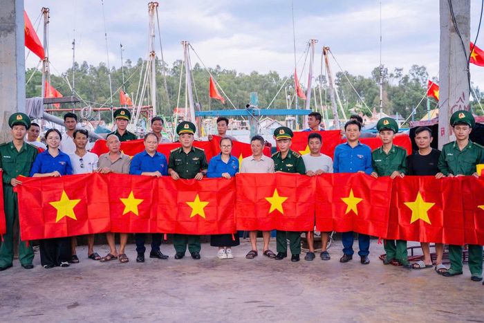Tuổi trẻ Đồn Biên phòng Quỳnh Thuận, Bộ đội Biên phòng tỉnh Nghệ An phối hợp đoàn viên thanh địa phương trao tặng cờ Tổ quốc cho ngư dân. (Ảnh: LÊ THẠCH)