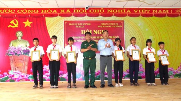 Đại tá Rơ Lan Ngân, Phó Chính ủy Ban Chỉ huy Bộ đội Biên phòng tỉnh Đắk Lắk và Bí thư Đảng ủy, Chủ tịch Hội đồng nhân dân xã Buôn Đôn Nguyễn Công Dũng trao thưởng và trao thư khen của Ban Chỉ huy Bộ đội Biên phòng tỉnh Đắk Lắk cho các em học sinh có thành tích học tập tốt trong Dự án “Cán bộ, chiến sĩ Quân đội nâng bước em tới trường” trên địa bàn xã Buôn Đôn. (Ảnh: DÂN QUÂN)