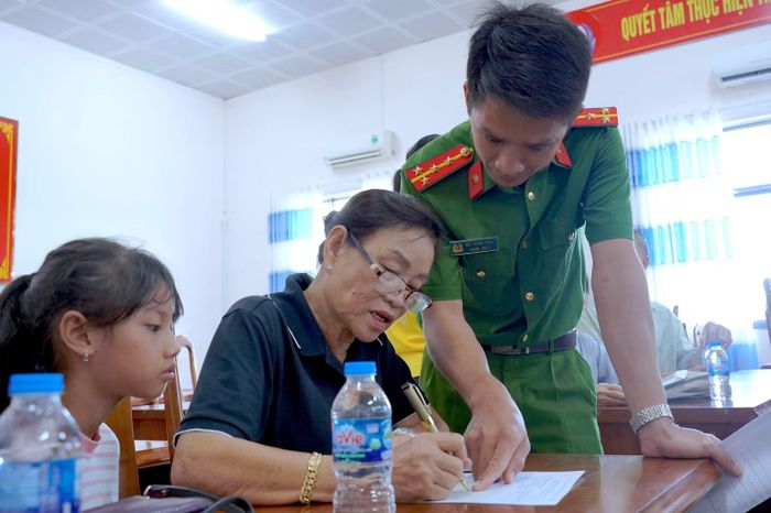 Cán bộ Công an xã, phường tại Cà Mau tích cực hướng dẫn thân nhân liệt sĩ kê khai thông tin trước khi thu nhận mẫu ADN. (ảnh HỮU ĐỆ).