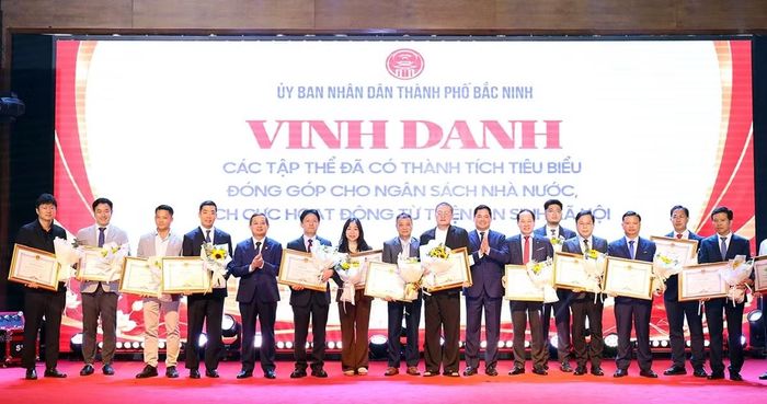 Bí thư Thành ủy Nguyễn Hồng Thái (thứ 7 từ phải qua) và Chủ tịch UBND thành phố Phạm Hoàng Sơn (thứ 5 từ trái qua) trao Bằng khen của Chủ tịch UBND thành phố cho các tập thể có thành tích tiêu biểu đóng góp lớn cho ngân sách nhà nước năm 2025.