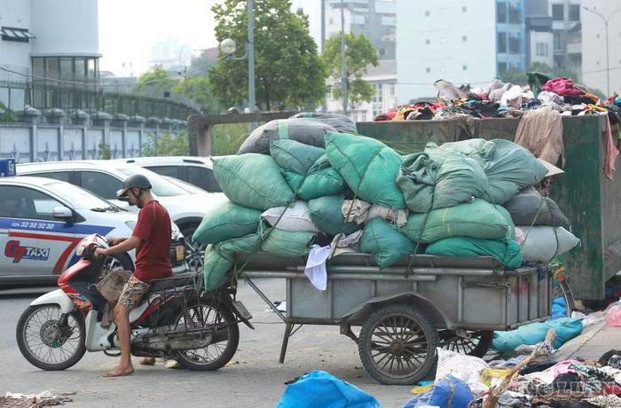 Nhiều lượt xe ba gác chở các bao quần áo ra khỏi khu vực tập kết.