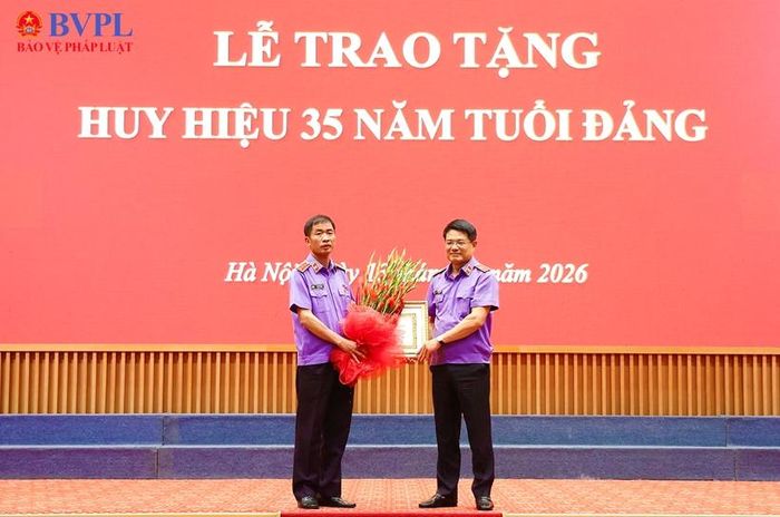 Đồng chí Nguyễn Huy Tiến, Bí thư Đảng ủy, Viện trưởng VKSND tối cao trao Huy hiệu 35 năm tuổi Đảng và tặng hoa chúc mừng đồng chí Nguyễn Duy Giảng.