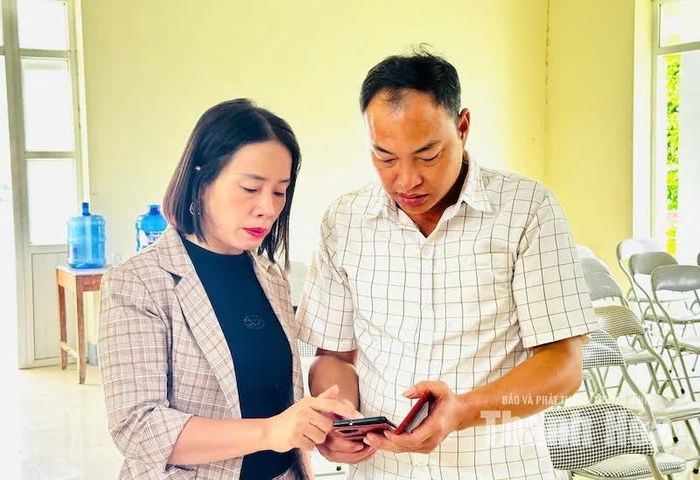 Cán bộ Mặt trận hướng dẫn người dân cài đặt ứng ụng Tiện ích số ThanhHoa.