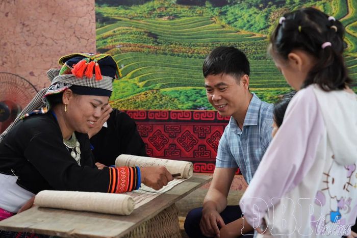 Du khách thích thú tìm hiểu kỹ thuật vẽ hoa văn bằng sáp ong trên vải lanh của phụ nữ Mông, thêm những trải nghiệm gần gũi, đáng nhớ tại ngày hội.