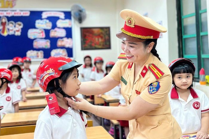 Thiếu tá Đoàn Ngọc Huyền, hướng dẫn học sinh lớp 1 đội mũ bảo hiểm an toàn.