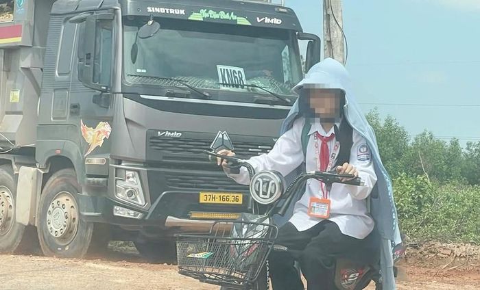 Học sinh đi học trên mặt đường bụi bặm, bùn đất do đoàn xe kéo từ trong mỏ ra ngoài. Ảnh: HQ