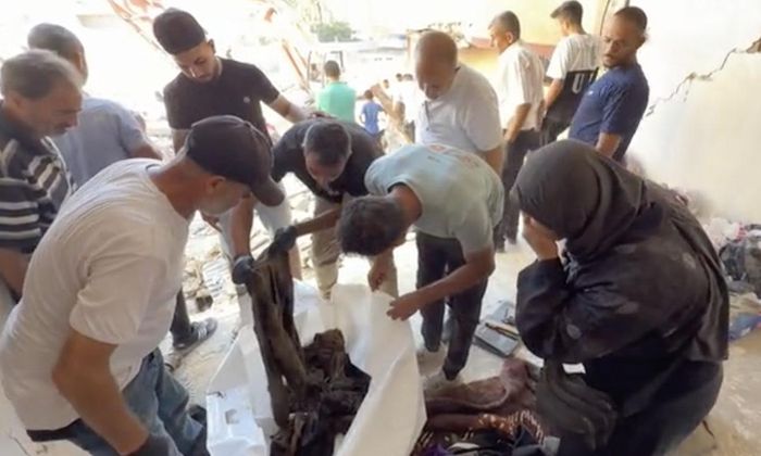 Một phụ nữ Palestine nhận dạng hài cốt của mẹ cô ở Tuffah, thành phố Gaza bằng cách nhìn vào quần áo của bà - Ảnh: CNN