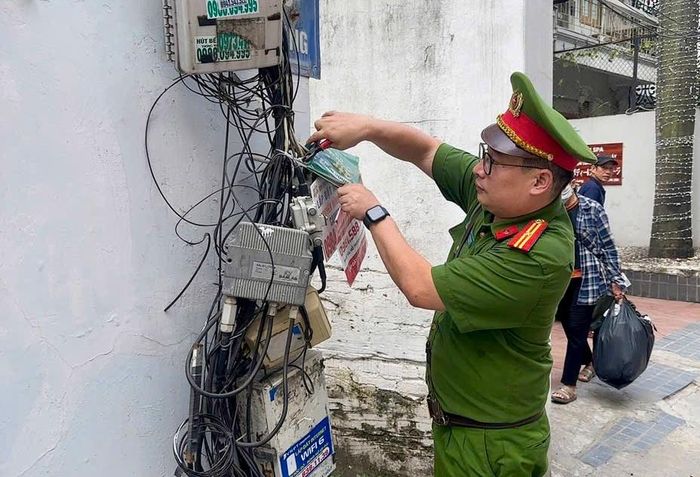 Lực lượng công an phường Ngọc Hà bóc xóa quảng cáo, rao vặt trái phép trên cây xanh, cột điện, tủ điện, tường rào và công trình công cộng. Ảnh: Duy Khánh