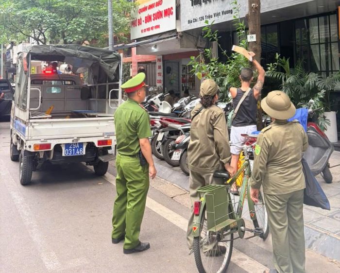 Người vi phạm dán quảng cáo ra vặt này buộc phải "lao động công ích" dưới sự giám sát của lực lượng chức năng và người dân. Ảnh: Bảo Hân