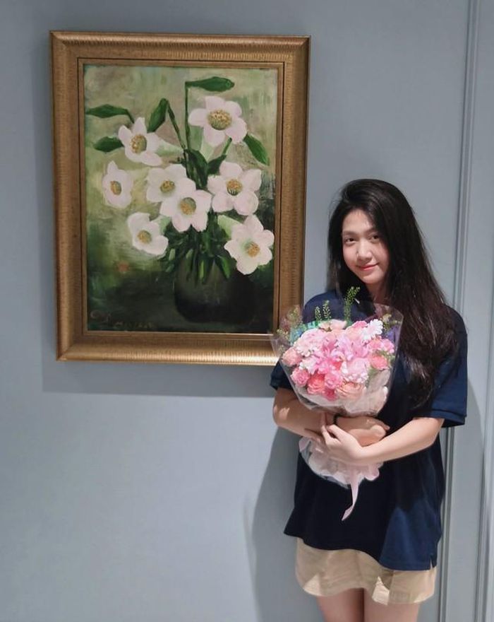 Con gái Mạnh Trường bên bức tranh do chính tay cô bé vẽ.