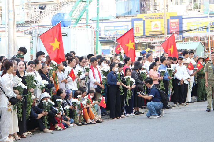 Rất đông người dân TPHCM đứng hai bên đường (đoạn vào cổng chính Công viên Lê Thị Riêng) để cầu nguyện và tiễn đưa các anh hùng liệt sĩ về nơi an táng. Ảnh: QĐ.