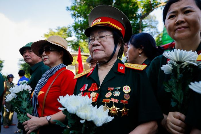 Bà Vũ Thị Minh Cái (85 tuổi, sống ở quận Tân Phú cũ) xúc động khi hay tin hài cốt các liệt sĩ sau nhiều năm nằm dưới lòng đất đã được tìm kiếm, quy tập và đưa về nơi an nghỉ cùng đồng đội. Dù tuổi cao, chân đau, đi lại khó khăn, bà vẫn cố gắng có mặt từ sớm để tiễn đưa các liệt sĩ. "Những bông hoa này là tấm lòng thành kính, trân trọng và tinh khiết nhất mà chúng tôi muốn gửi đến các anh. Có những người hy sinh khi tuổi đời còn rất trẻ, mới 18-20 tuổi, chưa lập gia đình. Sau bao nhiêu năm, việc tìm kiếm, quy tập được hài cốt các anh để đưa về nghĩa trang là điều vô cùng trân quý", bà Cái chia sẻ. Ảnh: Phương Lâm.